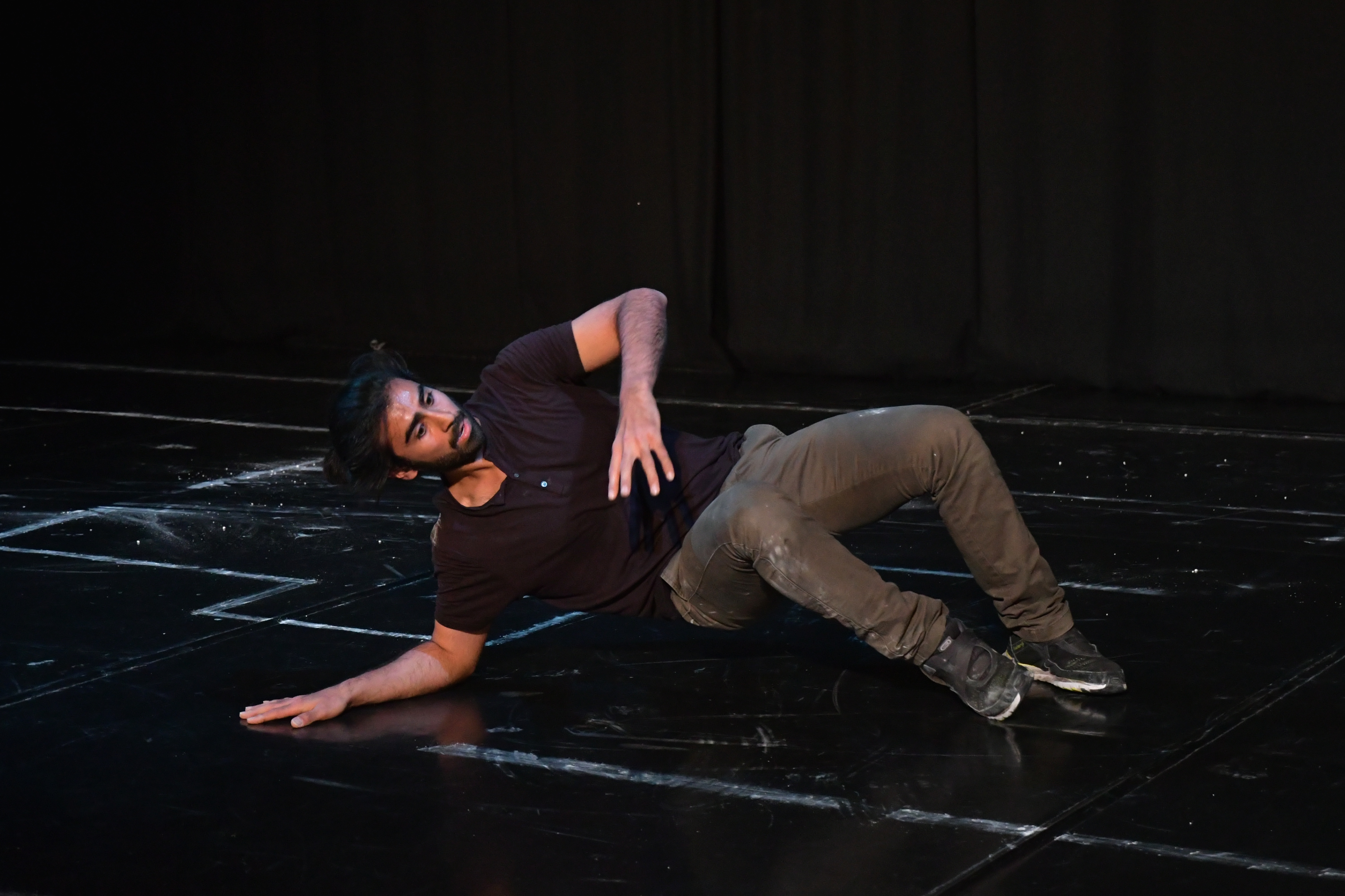 performer laying on his back. Black stage and black background