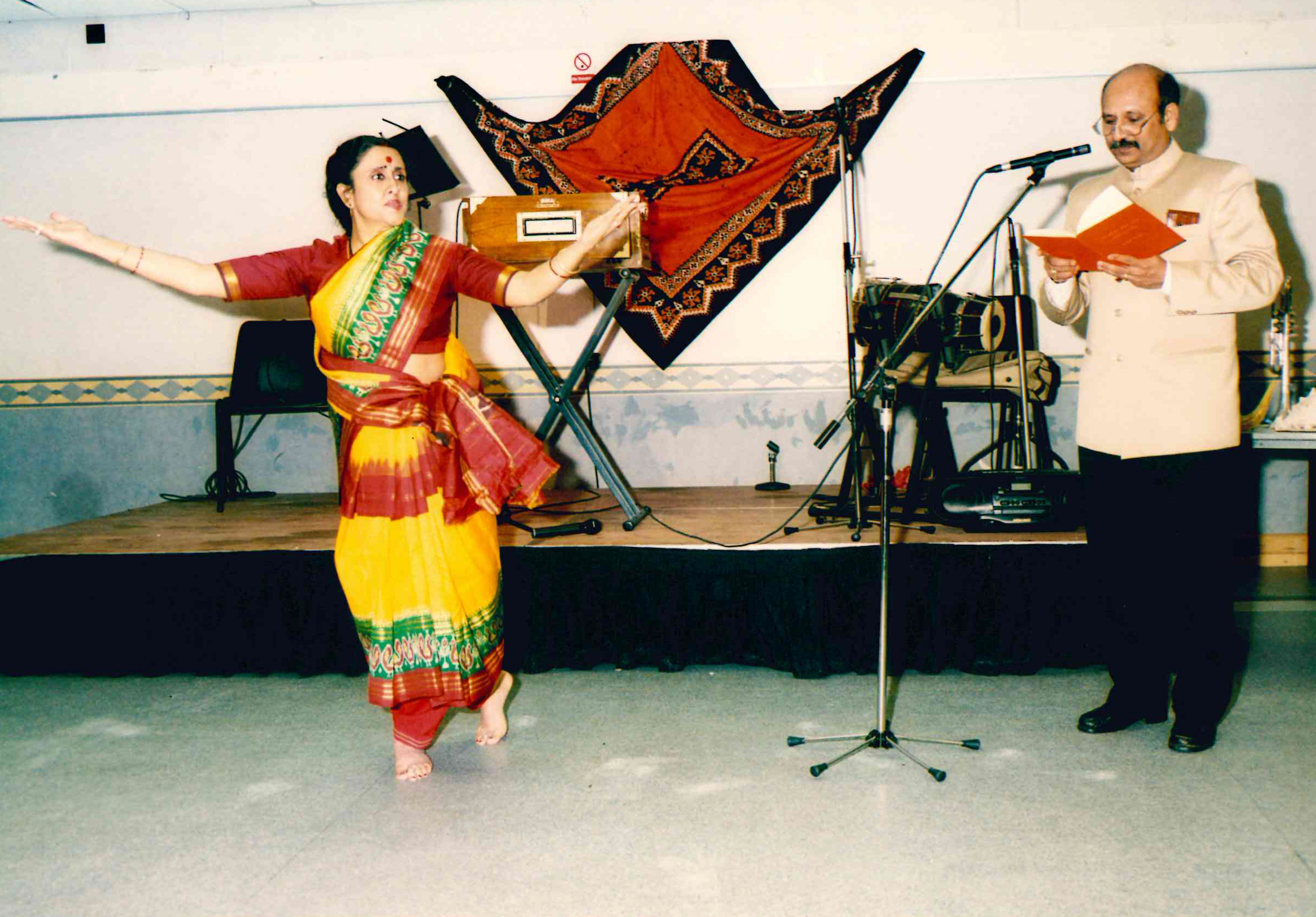 traditional south asian performers wearing traditional clothing. Singer on the right and dancer on the left.