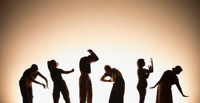 six performers in silhouettes- bright light in the background