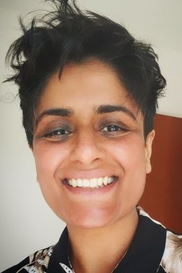 Headshot of a smiling South Asian woman with short hair