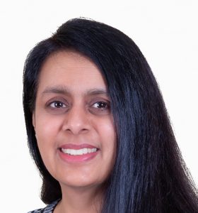 Head shot of a South Asian women with long dark hair smiling at the camera