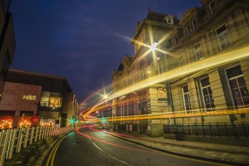 An photograph of Kala Sangam taken at night. Light trails are visible in front of the building from passing vehicles.