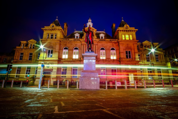 Kala Sangam (1 St Peters House) at night. Light trails are visible in front of the building from passing vehicles.