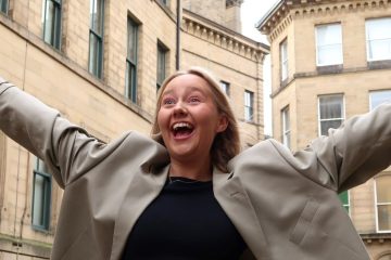 A young person holding out their arms in a city