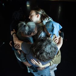 a group of dancers hugging on stage