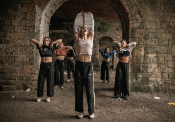 a group of dancers with their arms in the air inside an old building
