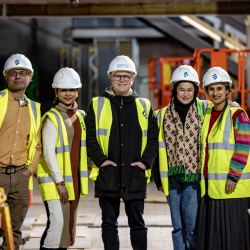 5 people in high vis jackets and helmets smiling towards the camera