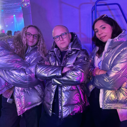 3 people wearing silver shiney coats in a purple rool
