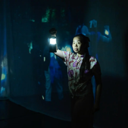 A woman holding up a lantern in a dark stage
