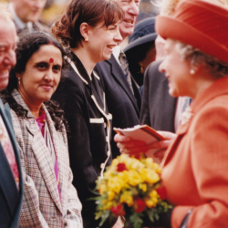 A photo of a woman meeting the queen who is wearing a pink hat and coat