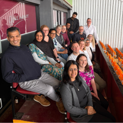 A photo of a group of people sat on chairs all smiling at the camera