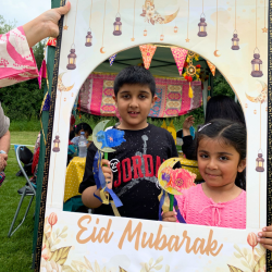 Two children holding up a picture frame that reads 'Eid Mubarak'